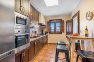 a kitchen with wooden cabinets and a table with chairs at Cortijo Jiménez in Pitres