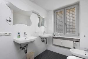 a white bathroom with two sinks and a window at Aldars Urban Grand Suite No.15 in Munich +20 photos