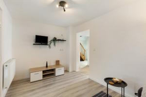 a white living room with a tv and a table at Casa Verde Sauerland in Lennestadt
