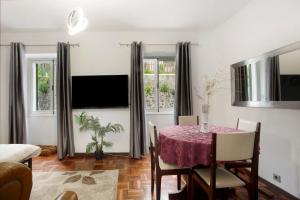 a dining room with a table and chairs and a tv at Carros De Cesto Do Monte in Funchal