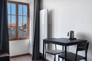 a black table and chair in a room with a refrigerator at Chambres d'hôtes Le Plessis in Frossay