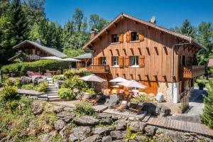 a large wooden house with chairs and umbrellas at Au Rêve Savoyard 6 - 4 personnes in Morillon