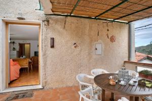 a patio with a wooden table and white chairs at Câ de Bacî in Vessalico