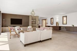 a living room with white furniture and a flat screen tv at Villa Valériane in Trans-en-Provence
