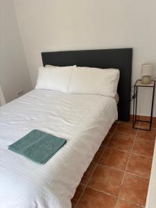 a white bed with a green towel on it at Apartamento centro 1-B in Huelva