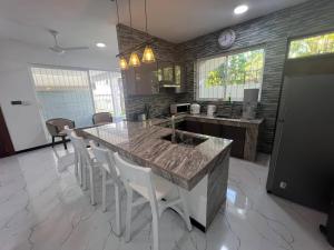 a kitchen with a large island with a sink and white chairs at Luxe Mini-Suite Maharagama in Maharagama