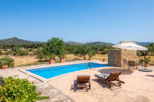 a pool with chairs and a table and an umbrella at Can Carboneta in Artá