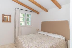 a white bedroom with a bed and a window at Charming house in San Pantaleo in Olbia +20 photos