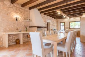 a dining room with a wooden table and white chairs at Son Rossinyol Nou - 12 personas in Islas Baleares