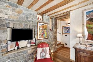 a living room with a stone wall with a flat screen tv at Il Cuore della Valdigne in Morgex