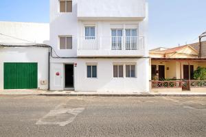 a white house with a green door on a street at Campo Amor Bajo in Arrecife