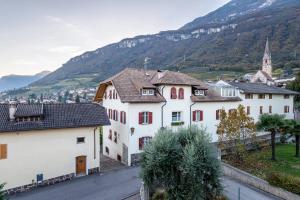 a village with white buildings and mountains in the background at Ferienwohnungen Karin - Cabernet in Termeno