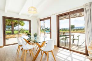 a dining room with a glass table and white chairs at Sa Caseta Biniali in Biniali