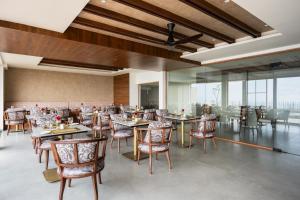 a dining room with tables and chairs and windows at Olive Woods in Chinnakanal