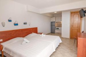 a bedroom with a large white bed and a kitchen at Anemologio 202 Studio Tinos in Agios Ioannis