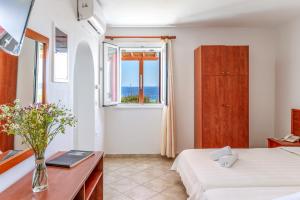 a bedroom with a bed and a desk and a window at Anemologio 202 Studio Tinos in Agios Ioannis
