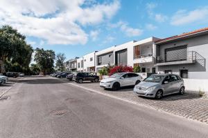 a row of cars parked in a parking lot next to a building at Quarto do Papagaio in Palmela