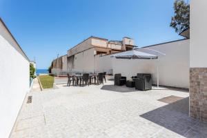 a patio with a table and chairs and an umbrella at Villa Mare Blu in Palermo