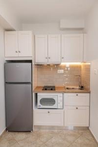 a kitchen with white cabinets and a stainless steel refrigerator at Anemologio 202 Studio Tinos in Agios Ioannis