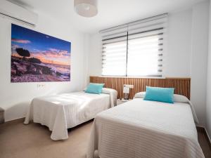 two beds in a room with a painting on the wall at 'Mi Esperanza' in Almuñécar