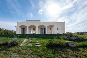 a white house in a field with the sun in the sky at Casale 50 Elegante Villa a Otranto in Otranto