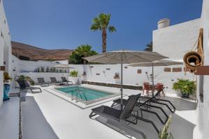 a patio with a pool and chairs and an umbrella at Arrieta Costa Rural in Tabayesco