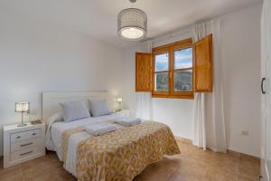a white bedroom with a bed and a window at Villa picena las alpujarras in Picena