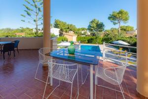 a patio with a glass table and chairs at Ca Na Xisca in Sa Coma