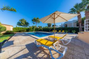a pair of chairs and an umbrella next to a swimming pool at Ca Na Xisca in Sa Coma