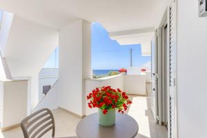 a vase with red flowers on a table in a room at Residence Fronte Mare in Ugento