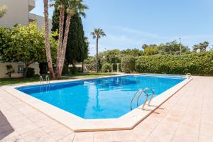 a swimming pool with blue water and palm trees at Boliche in Benimagrell