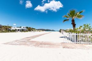 a beach with a white fence and a palm tree at Casa Perla in Villasimius