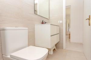 a white bathroom with a toilet and a mirror at Los Delfines Biniforcat in Ciutadella +19 photos