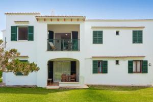 a white house with green shutters and a yard at Los Delfines Biniforcat in Ciutadella