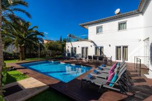 a swimming pool with chairs and a house at Villa Amarador in Santanyi