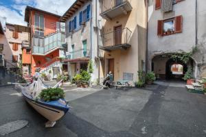 a man sitting on a bench in a street with buildings at Le Volte - Lago D'Iseo in Pisogne