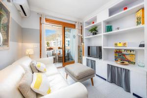 a living room with a white couch and a television at Formentorgloria in Port de Pollensa