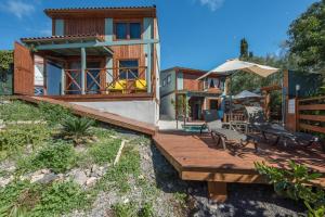 a house with a wooden deck with chairs and an umbrella at Las Hermanas A y B in Guía de Isora