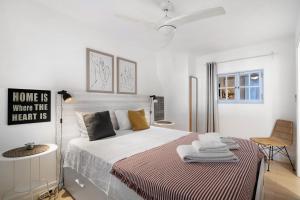 a white bedroom with a bed and a chair at Casa Amarela in Tavira