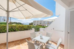 a patio with a white table and chairs and an umbrella at Apartamento Erizo de Mar in Felanitx