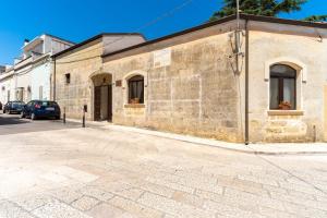 an old brick building on a street with cars parked outside at Dimora Pisanelli in Specchia