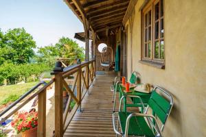 a wooden porch with green chairs and a table at L'Atelier de Scarlett - Lannux in Lannux