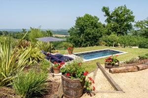 a garden with a swimming pool and flowers in buckets at L'Atelier de Scarlett - Lannux in Lannux