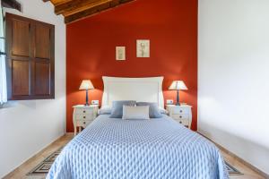 a bedroom with a large bed with a red wall at Las Candelas - Puerto Calderón in Oreña