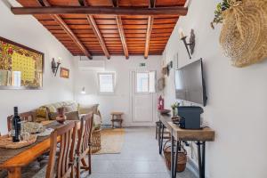 a living room with a table and chairs and a tv at Descanso Alentejano -Casa d'aldeia in Campinho