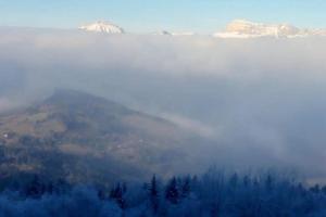 a view of a mountain with fog in the valley at Appart 7 Laux - Balcon Sud in Les Adrets