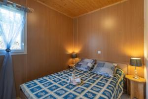 a bedroom with a bed with a blue comforter and a window at Maisons Cozy - Mas Lachamp in Gravières +41 photos