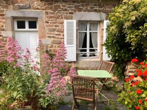 a table and chairs in front of a house with flowers at Keranroux 315 - Île de Bréhat in Bréhat +2 photos