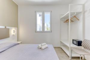 a white bedroom with a bed and a book shelf at Residence Fronte Mare in Ugento