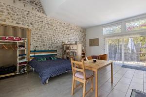 a bedroom with a bed and a desk and a table at Gîte L'ancien Préau in Avrillé-les-Ponceaux